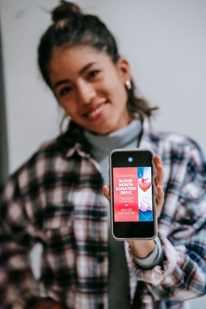 Services-01 Smiling woman holding smartphone displaying blood donation drive advertisement.